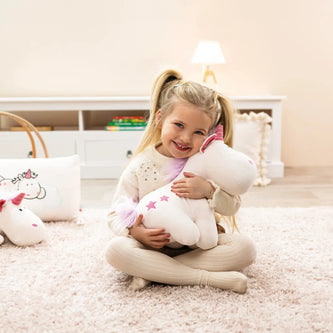 Kleines Mädchen sitzt im Kinderzimmer und umarmt ein Kuscheltier – weiches Plüschtier für Babys und Kinder