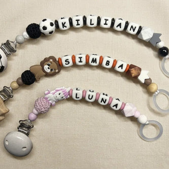Drei handgemachte personalisierte Schnullerketten von BabyLions® mit den Namen Kilian, Simba und Luna auf hellem Hintergrund