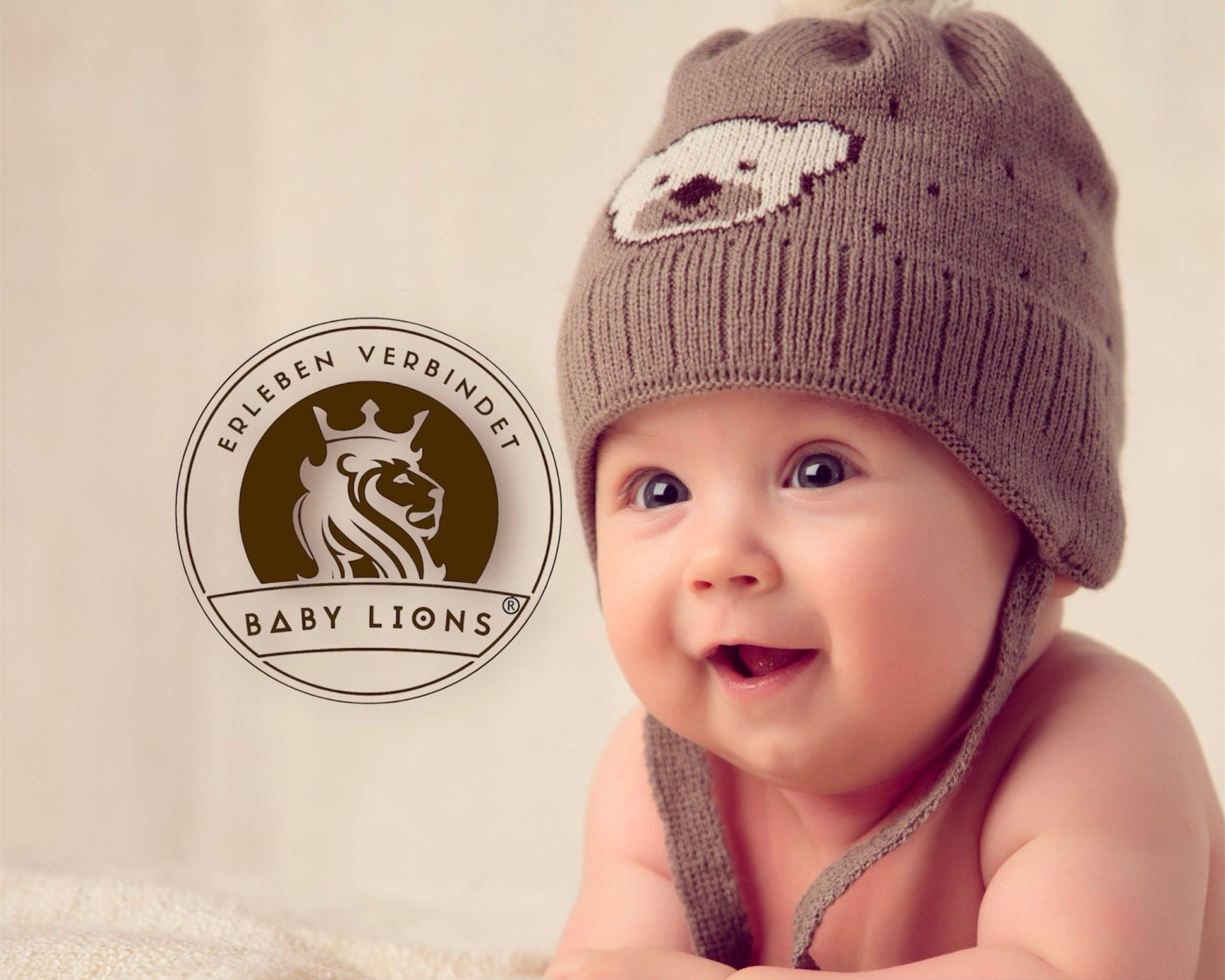 BabyLions® Baby mit Mütze – offizielles Logo Erleben verbindet, hochwertige Babyprodukte