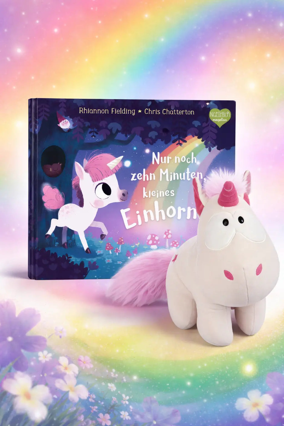Kinderbuch ›Nur noch zehn Minuten, kleines Einhorn‹ von Rhiannon Fielding mit Einhorn-Kuscheltier als Geschenk-Bundle vor märchenhaftem Einhorn-Hintergrund