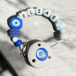 Personalisierte Schnullerkette mit Namen „Elias“ in Blau und Weiß mit Nazar Auge, Holzclip und Silikonperlen auf hellem Marmortisch