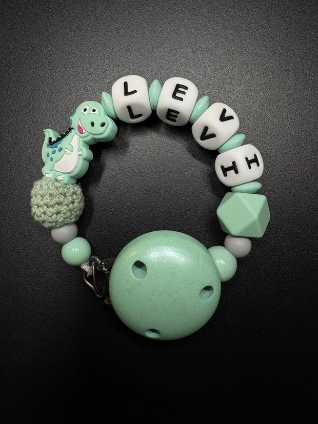 Personalisierte Schnullerkette Dino mit Namen in Mint aus Silikon- und Holzperlen mit Holzclip und Silikonring von BabyLions®