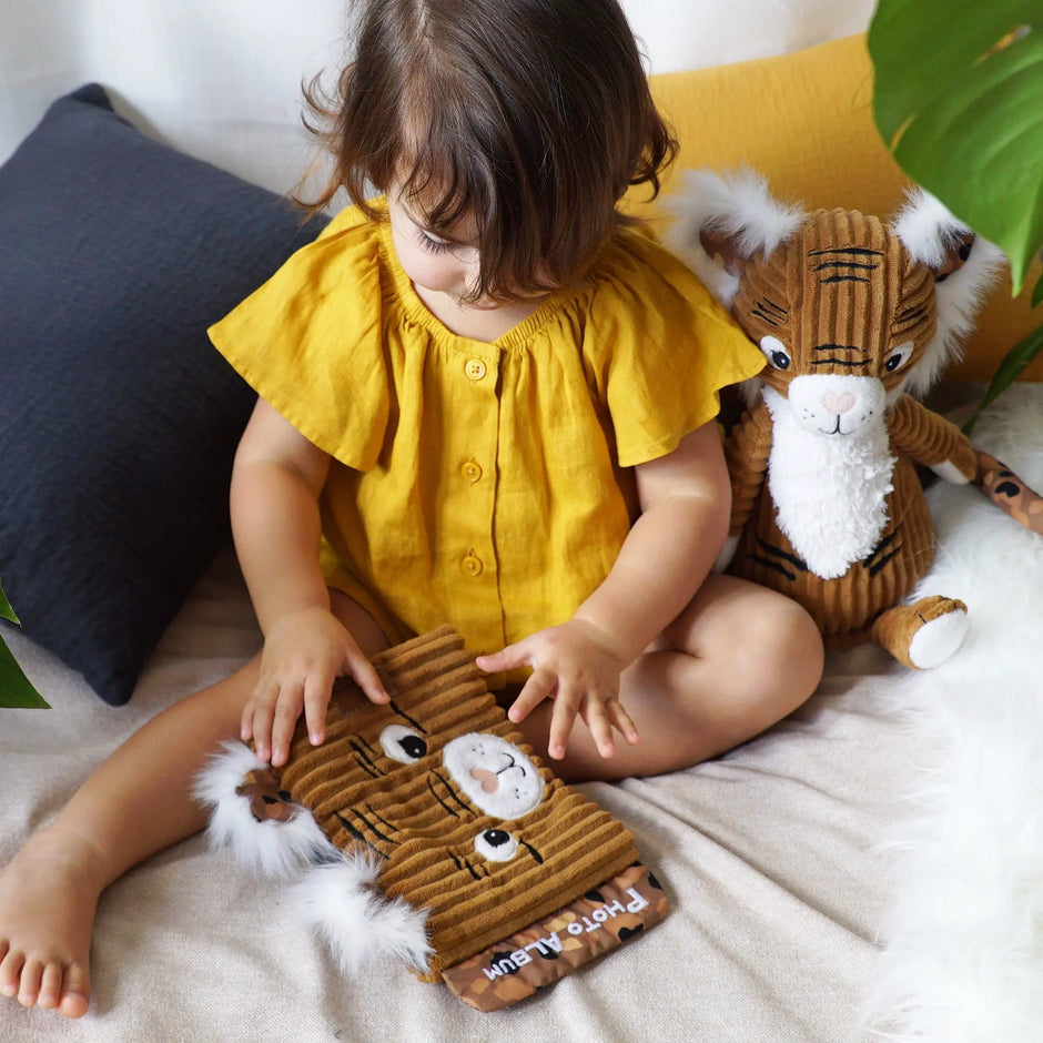 Baby spielt mit Fotoalbum Tiger Plüsch Spielzeug