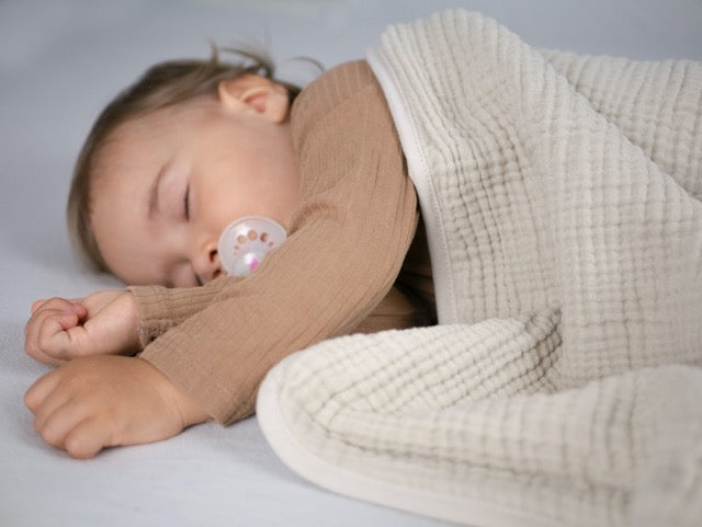 Schlafendes Baby unter sandfarbener Musselin-Babydecke – weich, atmungsaktiv und ideal für ruhige Schlafmomente