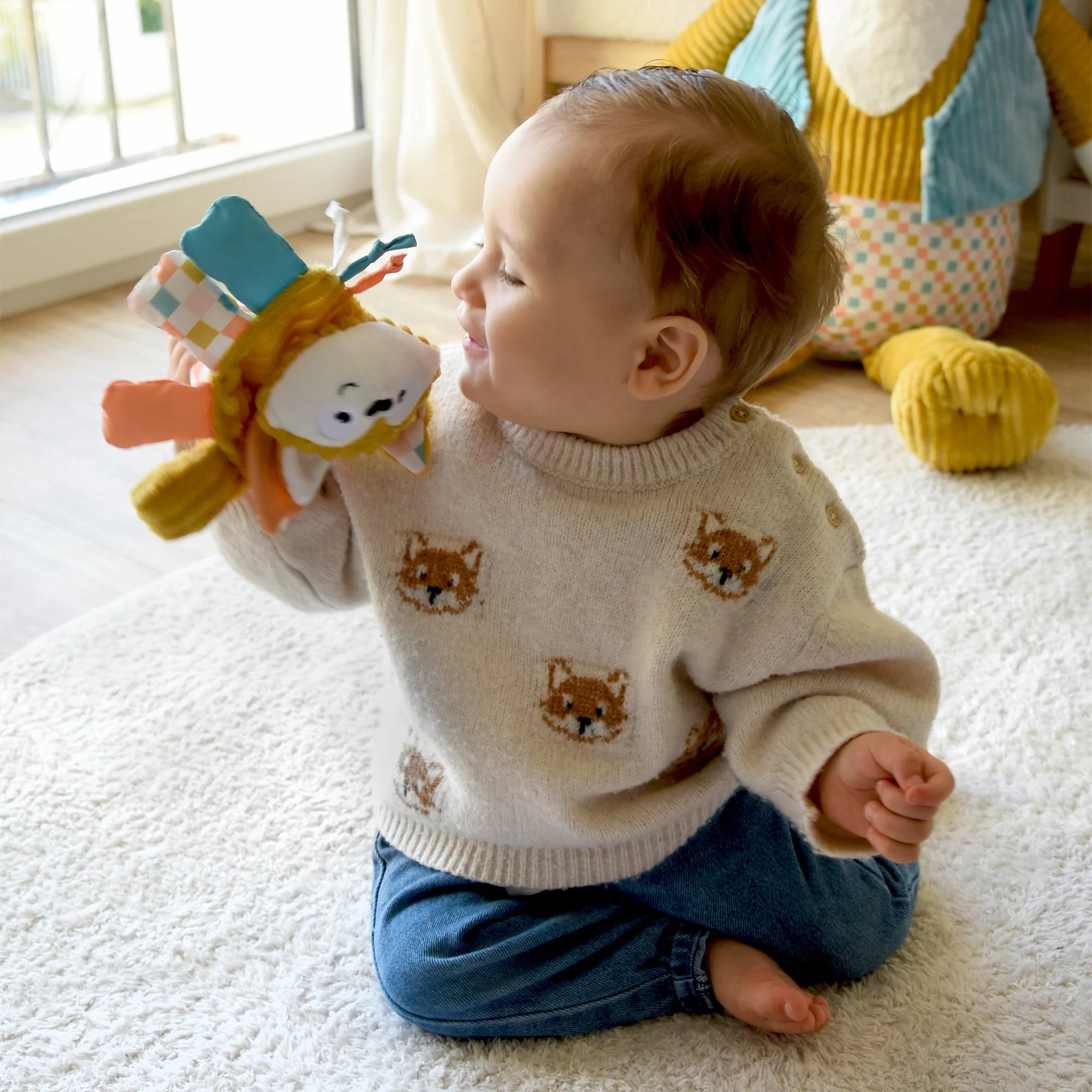 Baby spielt im Wohnzimmer mit einer weichen Fuchs Activity Rassel aus Stoff mit verschiedenen Greif- und Fühlelementen