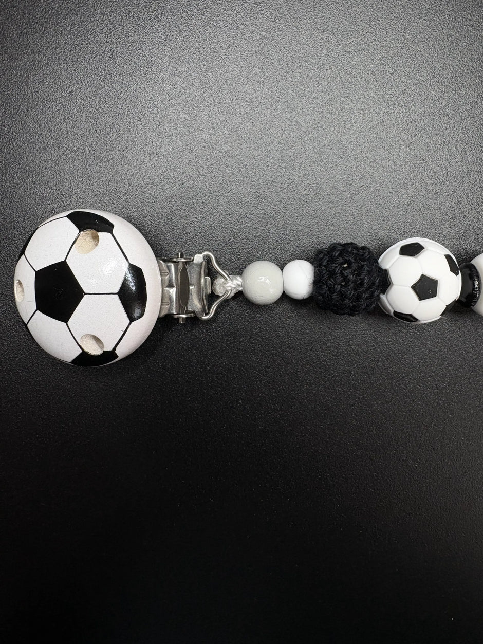 Detailaufnahme des Fußballclips und der Häkelperle der personalisierten Schnullerkette Kilian in Schwarz Weiß