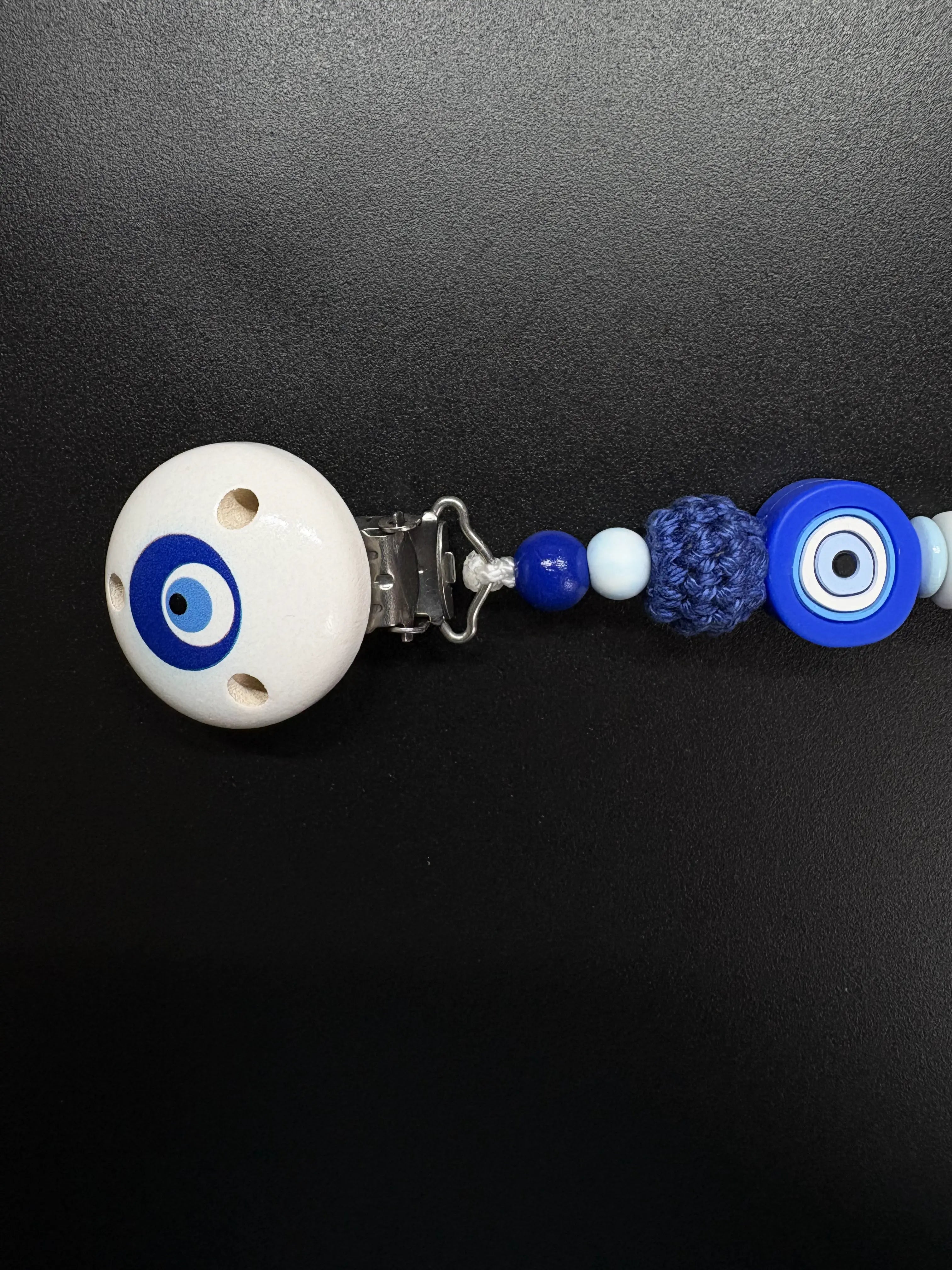 Detailaufnahme des Holzclips und der Häkelperle der personalisierten Schnullerkette Elias mit Bösem Auge