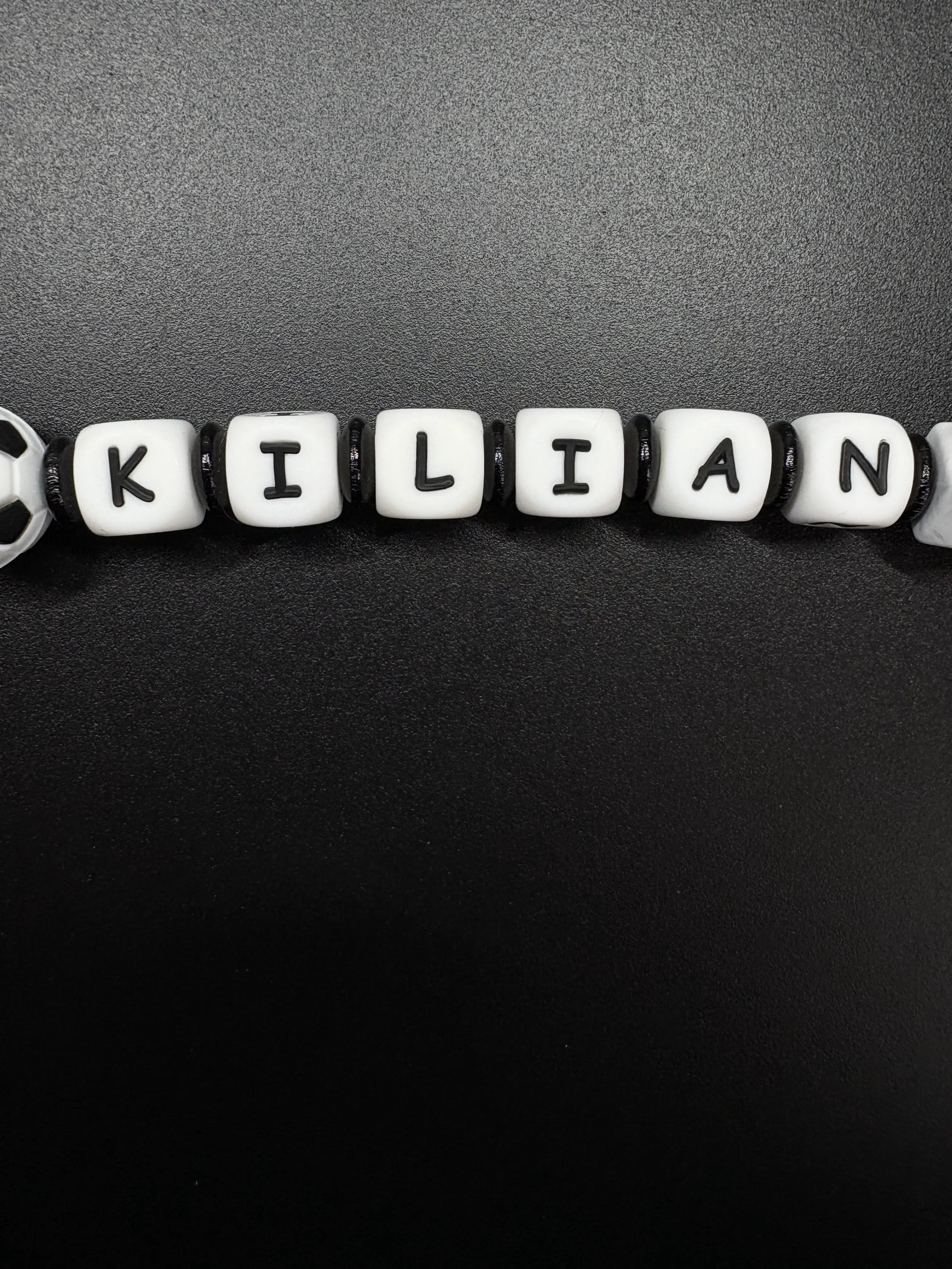 Detailaufnahme der personalisierten Fußball Schnullerkette mit dem Namen Kilian in Schwarz und Weiß