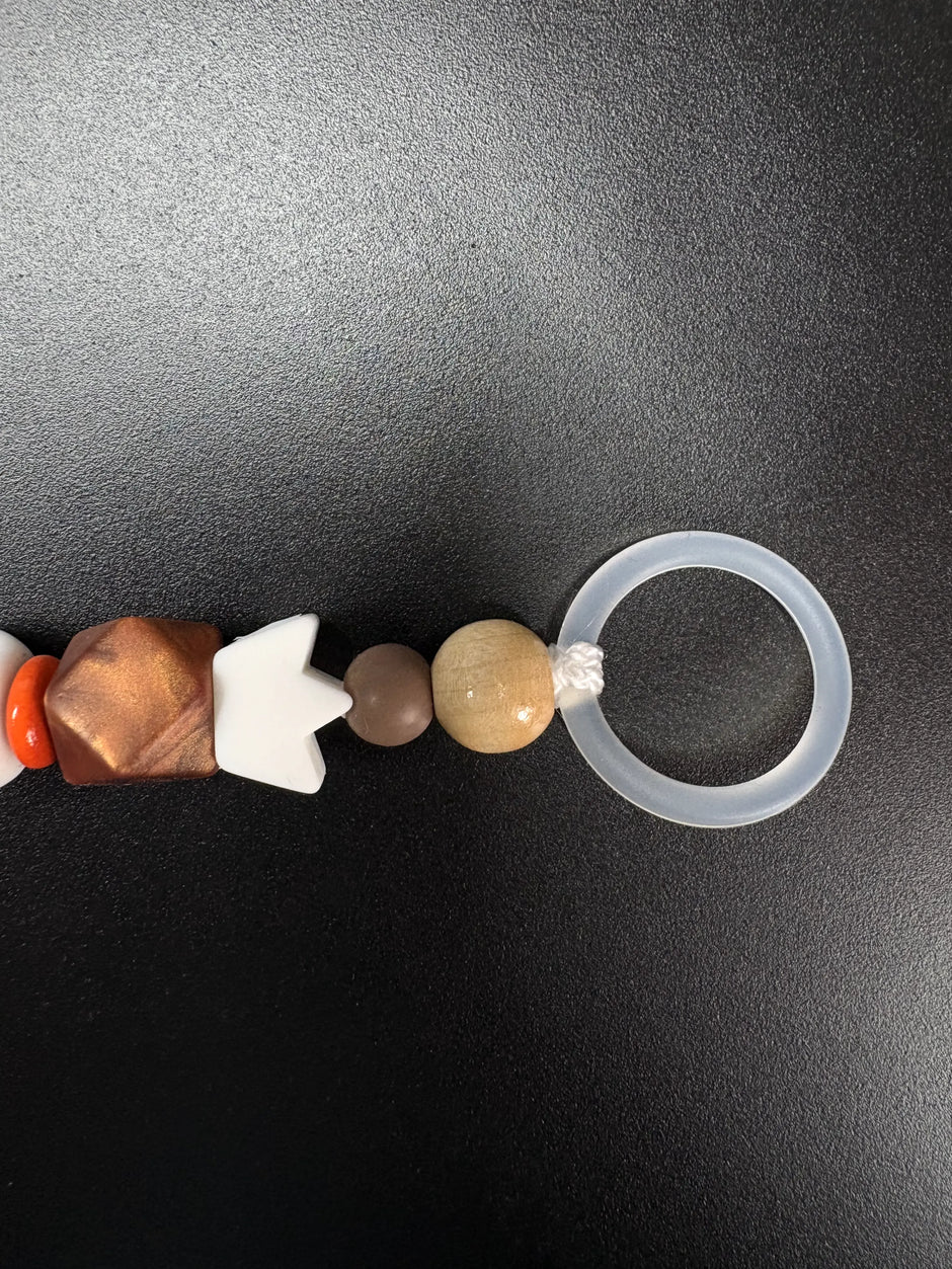 Detail der personalisierten Schnullerkette Simba mit Silikonring, braunen Holzperlen und orangefarbenen Akzenten